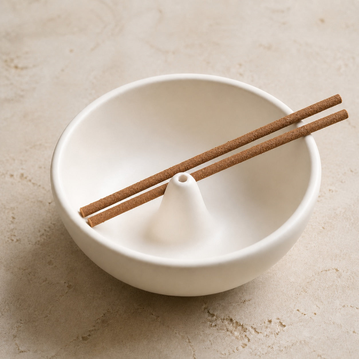 White bowl-shaped incense holder with a central opening and two incense sticks