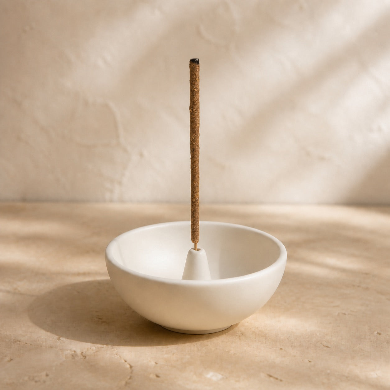 White bowl-shaped incense holder with one upright incense stick